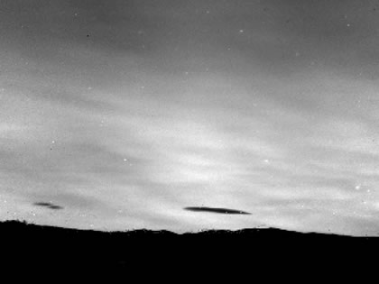copyright © Onera 2010 - Tous droits réservés Deux nuages apparaissent en contraste sur le fond du ciel illuminé par l'émission proche infrarouge induite par les molécules OH de la haute atmosphère. C'est le phénomène de nightglow.